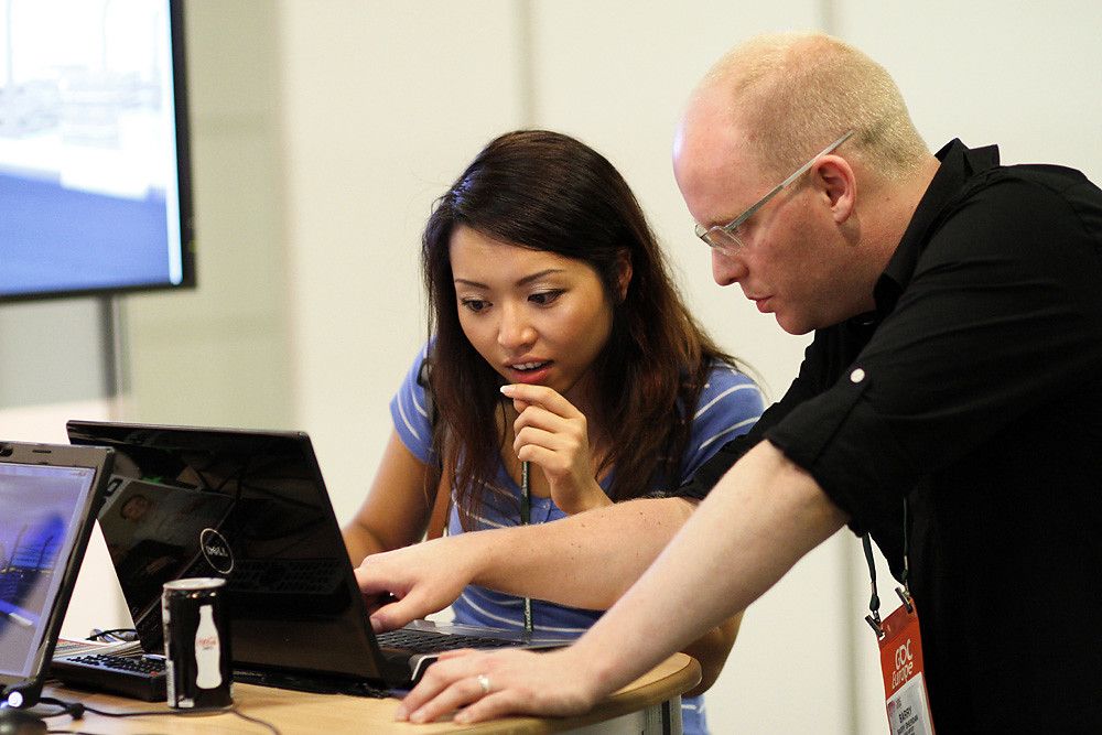 A salesperson demonstrating software on a laptop to a visitor at a conference