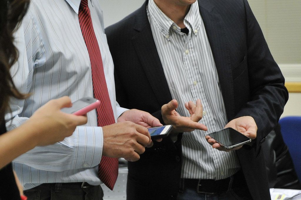 Two professionals holding smartphones while exchanging contact details at a meeting